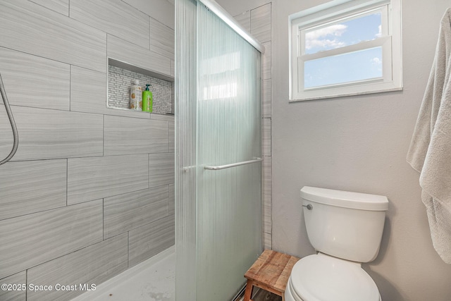 bathroom featuring toilet and a shower with door