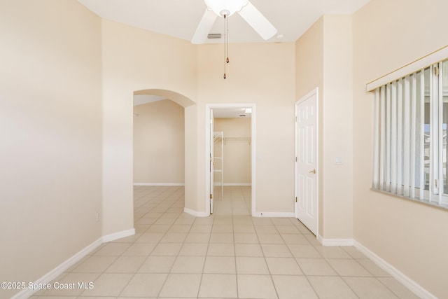 tiled spare room with ceiling fan and a towering ceiling