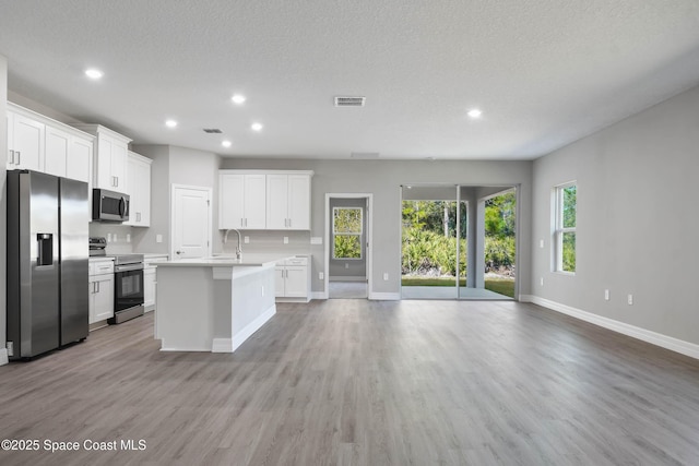 kitchen with white cabinetry, sink, a kitchen island with sink, light hardwood / wood-style floors, and stainless steel appliances