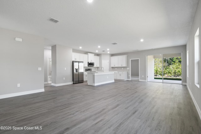 unfurnished living room featuring wood-type flooring, sink, and a textured ceiling