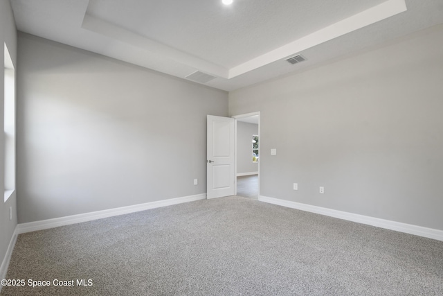 empty room featuring carpet flooring and a tray ceiling