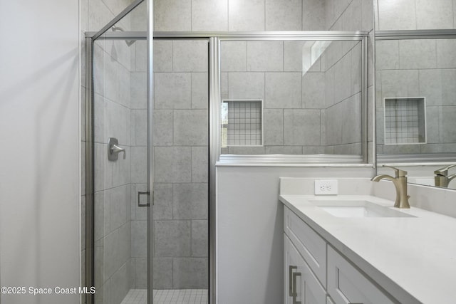 bathroom featuring a shower with door and vanity