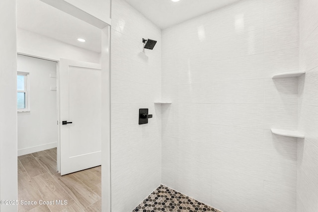 bathroom featuring a tile shower and wood-type flooring