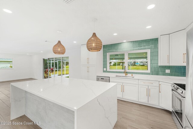 kitchen with white cabinets, decorative light fixtures, sink, and appliances with stainless steel finishes