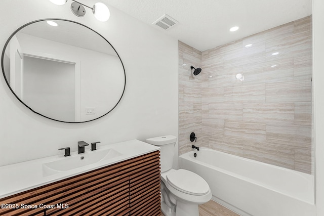 full bathroom with tiled shower / bath combo, toilet, a textured ceiling, and vanity