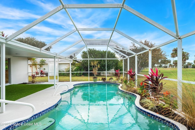 view of pool with a lawn, a patio area, and a lanai