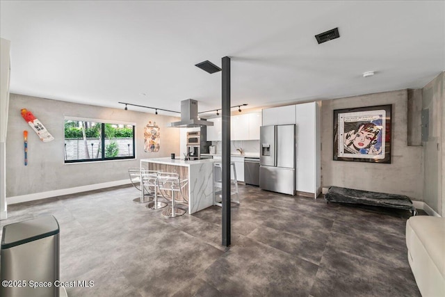 kitchen featuring island exhaust hood, a breakfast bar, stainless steel appliances, white cabinets, and concrete floors