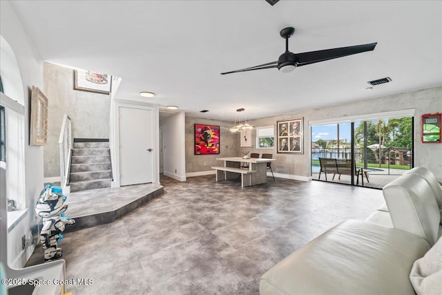 living room with concrete flooring and ceiling fan with notable chandelier