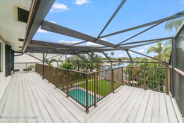 wooden deck featuring glass enclosure and a water view