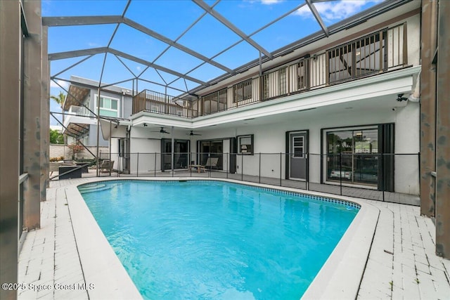 view of swimming pool with a patio, glass enclosure, and ceiling fan