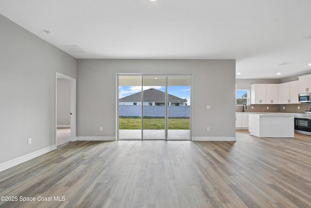 unfurnished living room with a wealth of natural light, light hardwood / wood-style flooring, and sink