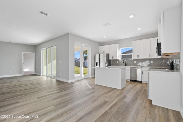 kitchen with a center island, stainless steel appliances, white cabinetry, and backsplash