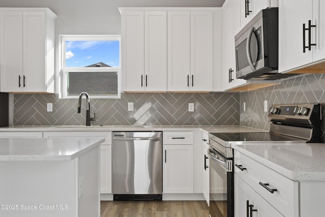 kitchen with white cabinetry, sink, stainless steel appliances, backsplash, and light hardwood / wood-style floors