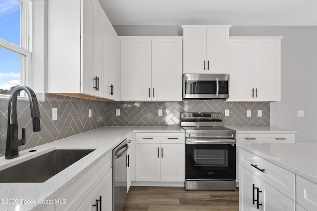 kitchen with light stone counters, sink, white cabinets, and appliances with stainless steel finishes