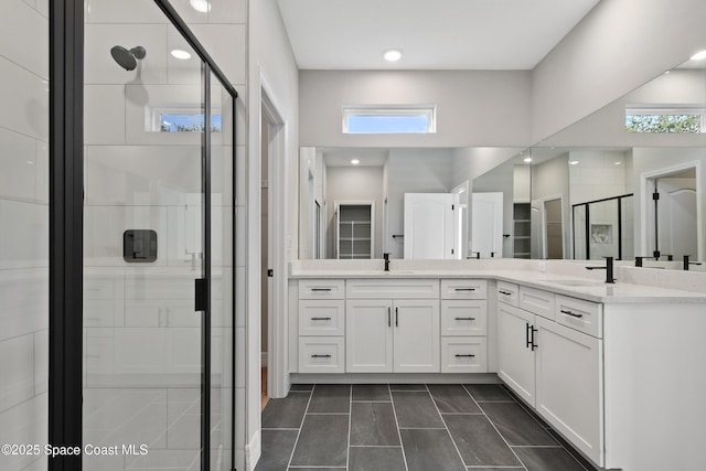 bathroom with tile patterned flooring, vanity, a wealth of natural light, and a shower with shower door