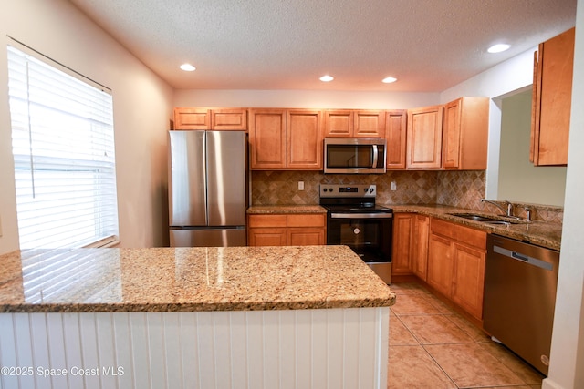 kitchen with sink, decorative backsplash, light tile patterned floors, light stone counters, and stainless steel appliances