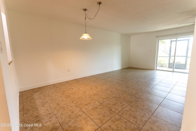 tiled empty room with ceiling fan and a textured ceiling