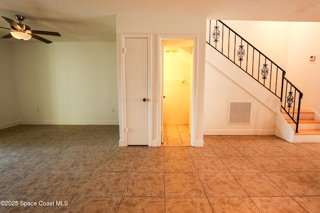 empty room with ceiling fan, tile patterned flooring, and a textured ceiling