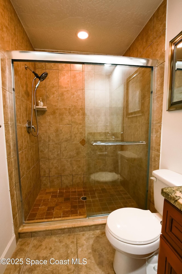 bathroom featuring tile patterned flooring, vanity, toilet, and a shower with shower door