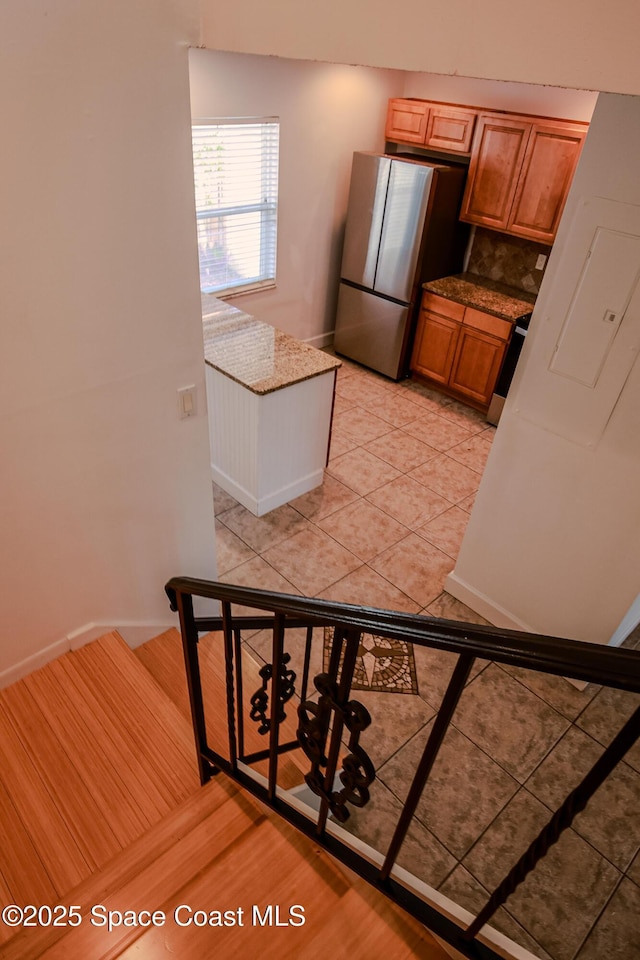 kitchen with backsplash, stainless steel refrigerator, light tile patterned flooring, and range