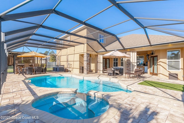 view of swimming pool featuring a patio area, glass enclosure, and an in ground hot tub