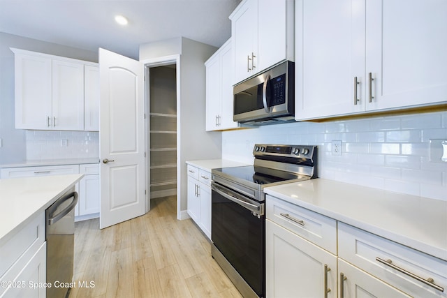 kitchen with stainless steel appliances, light countertops, and white cabinets