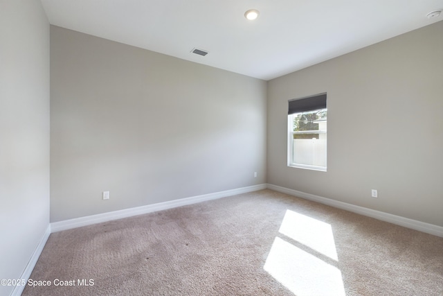 carpeted spare room featuring visible vents and baseboards