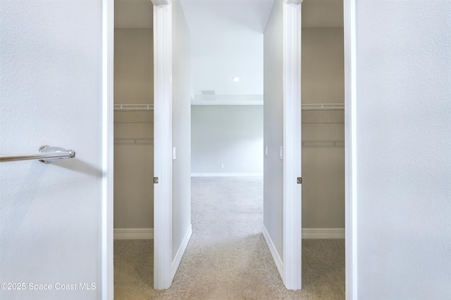 hall with light carpet, visible vents, and baseboards