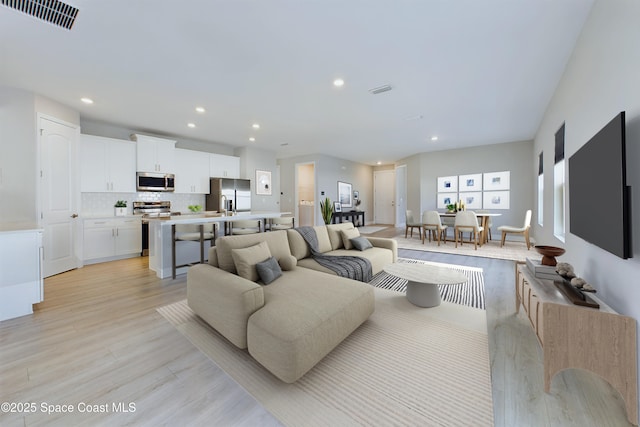 living area featuring light wood-type flooring, visible vents, and recessed lighting