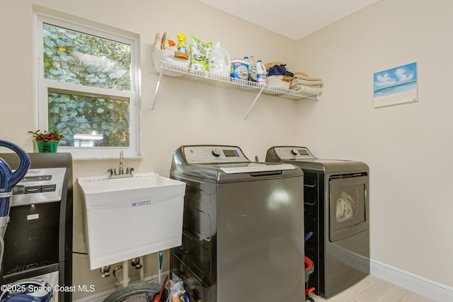 washroom with washer and dryer, light wood-type flooring, and sink