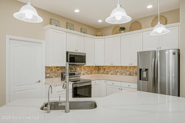 kitchen featuring decorative backsplash, stainless steel appliances, white cabinetry, and hanging light fixtures