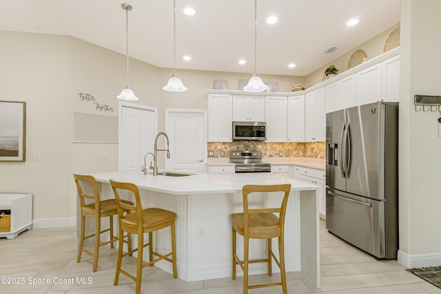 kitchen with white cabinetry, an island with sink, pendant lighting, and appliances with stainless steel finishes