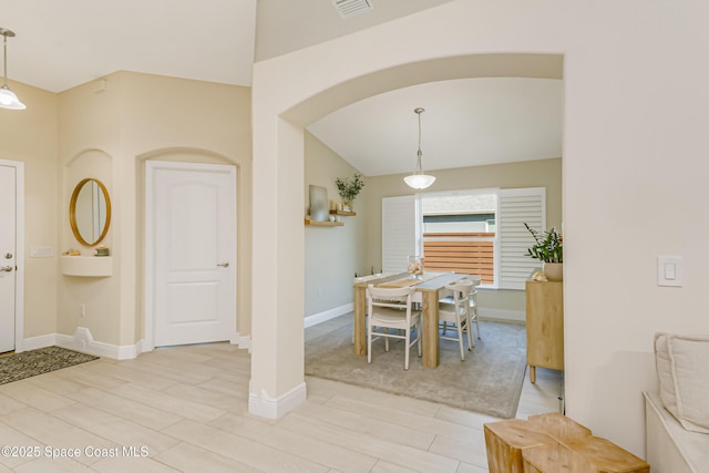 dining room with light wood-type flooring and vaulted ceiling