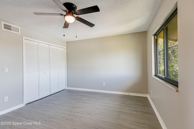 unfurnished bedroom with ceiling fan, a closet, a textured ceiling, and light hardwood / wood-style flooring