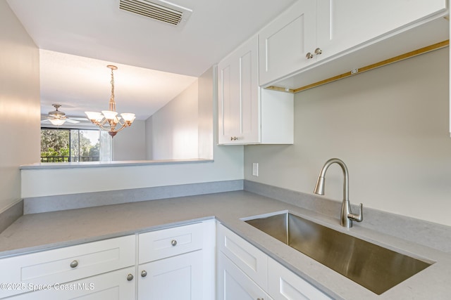 kitchen featuring white cabinets, ceiling fan with notable chandelier, hanging light fixtures, and sink