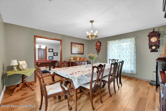 dining space with light hardwood / wood-style floors, a textured ceiling, pool table, and a chandelier