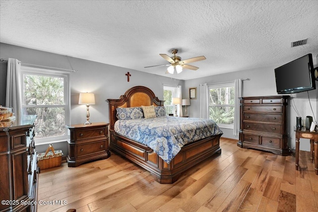 bedroom featuring a textured ceiling, light wood-type flooring, and ceiling fan