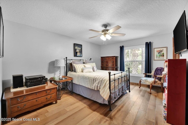 bedroom with ceiling fan, light hardwood / wood-style floors, and a textured ceiling