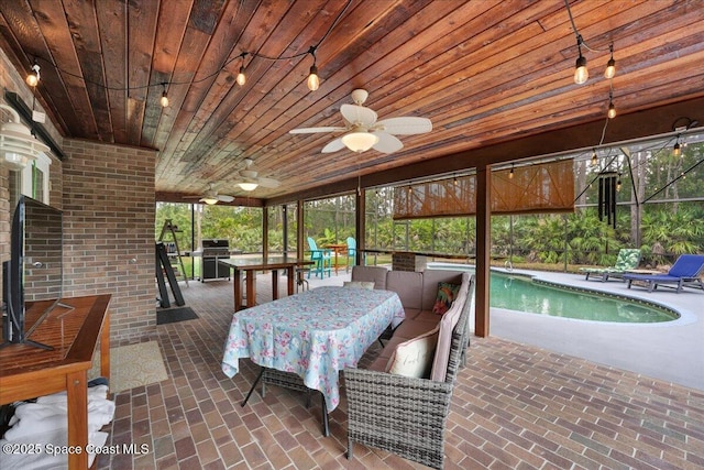 sunroom / solarium with a pool with hot tub, ceiling fan, and wood ceiling