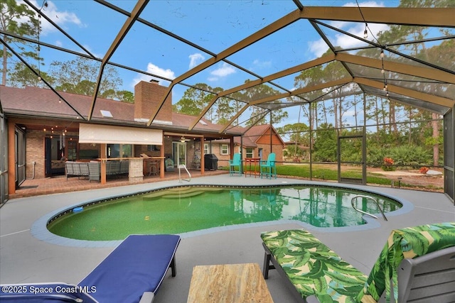 view of pool featuring a lanai, an outdoor kitchen, a grill, and a patio area