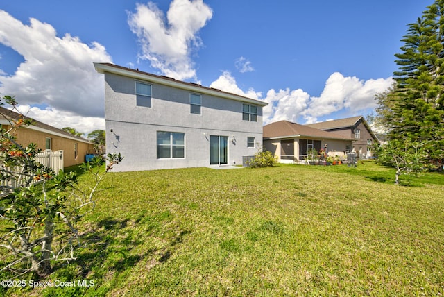 back of property featuring a lawn, fence, and stucco siding