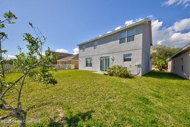 back of property with fence, a lawn, and stucco siding