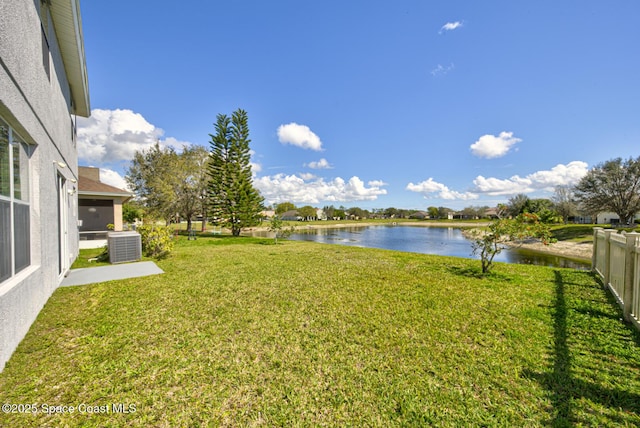 view of yard featuring a water view, fence, and central AC