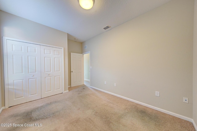 unfurnished bedroom featuring carpet floors, a closet, visible vents, and baseboards