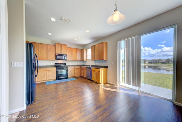 kitchen with a water view, visible vents, black appliances, dark countertops, and dark wood finished floors