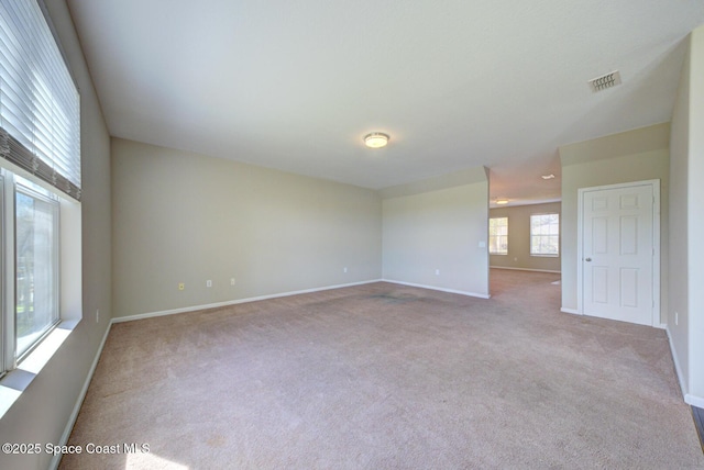 empty room featuring carpet, visible vents, and baseboards