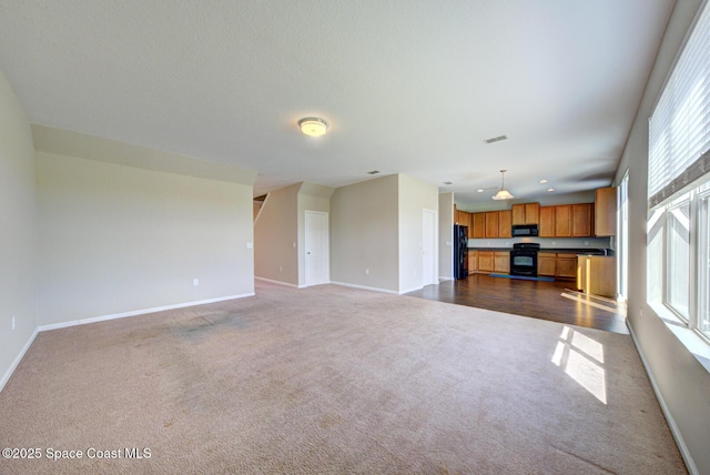 unfurnished living room with visible vents, baseboards, and dark colored carpet