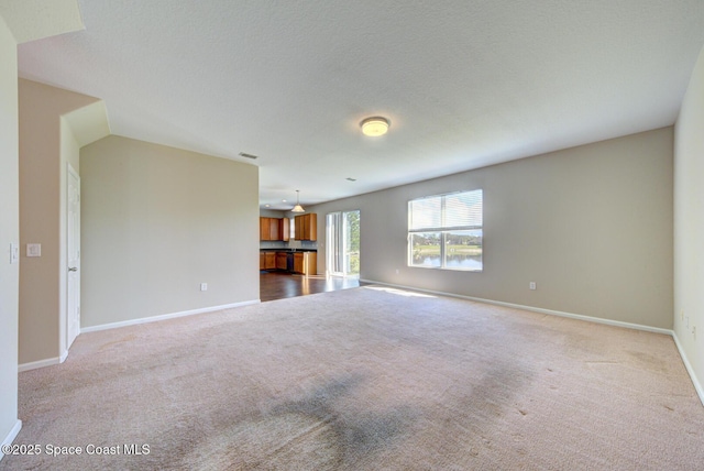 unfurnished living room with a textured ceiling, carpet, visible vents, and baseboards