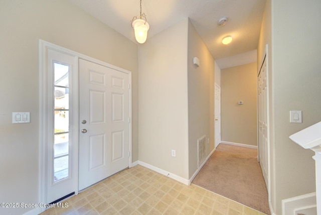 entrance foyer featuring light colored carpet, a healthy amount of sunlight, visible vents, and baseboards