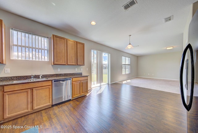 kitchen featuring visible vents, dishwasher, open floor plan, freestanding refrigerator, and a sink